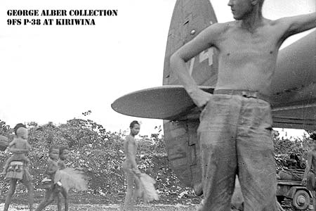 Island natives pass someone standing next to P-38 #74.